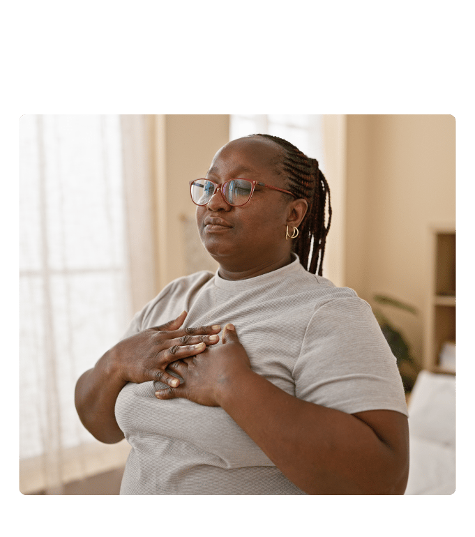 Woman with her hands over her chest taking a calming breath.
