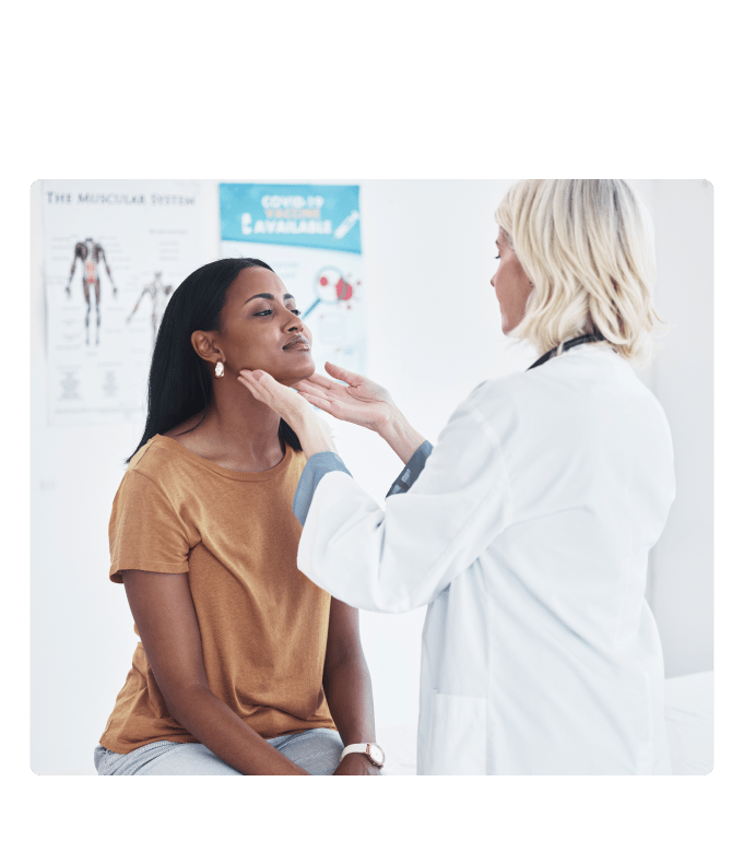 Provider in a white coat gently examines a seated person's neck in an exam room