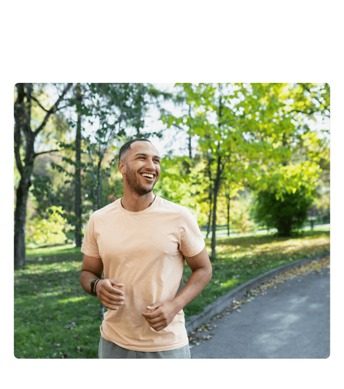 Smiling person jogs along a tree-lined path in a park