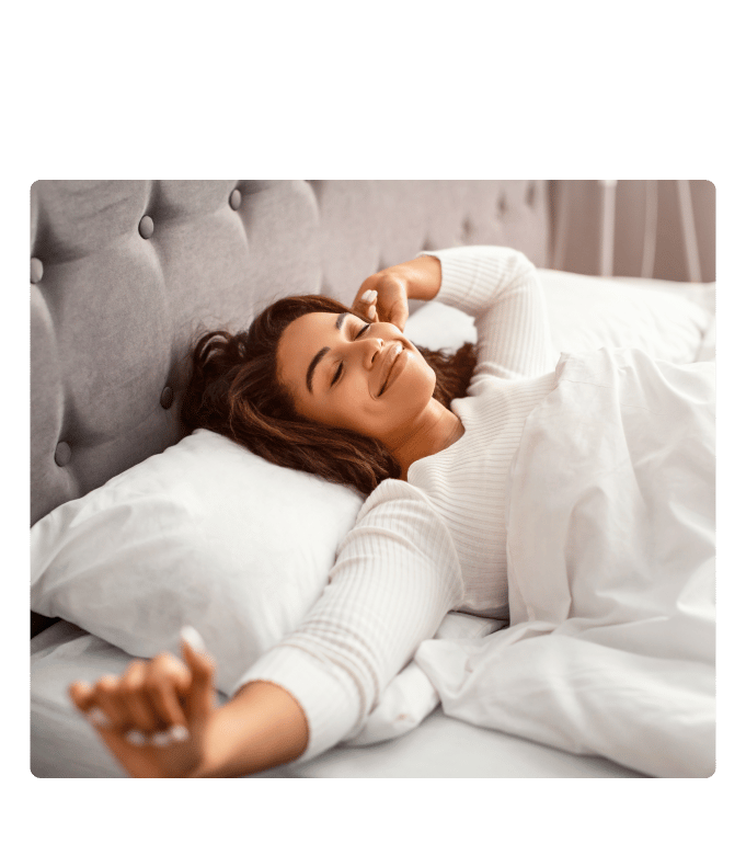 Person stretches with a relaxed smile while waking up in bed