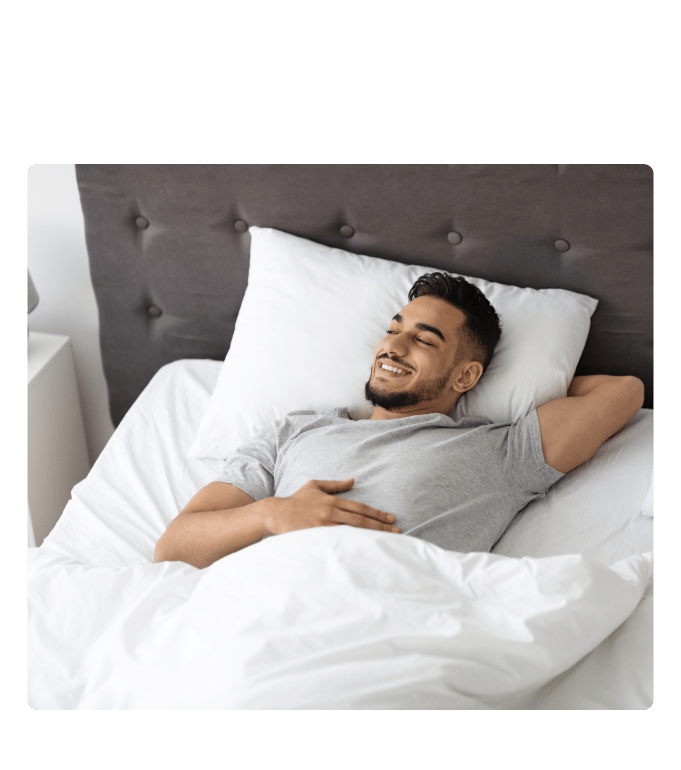 Person smiling with eyes closed while lying back on a pillow in bed